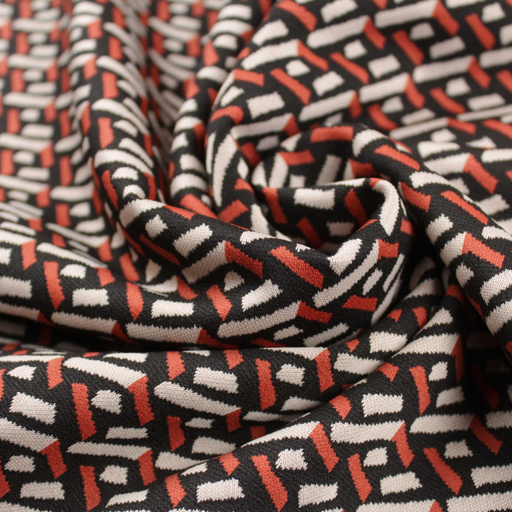 Tissu jersey noir motifs géométriques blancs et orange peu extensible